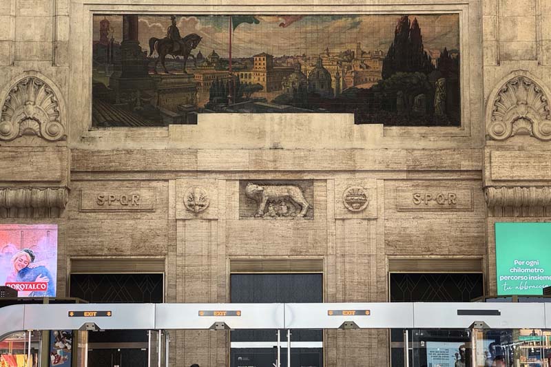 A tan wall with intricate carvings and a mural