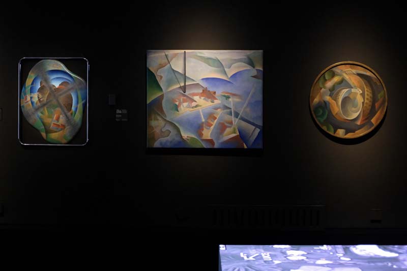 Three colorful pieces of art on a black wall
