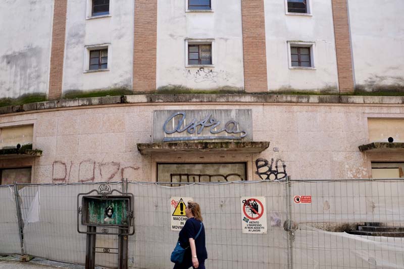 A person walking against a construction fence in front of a building