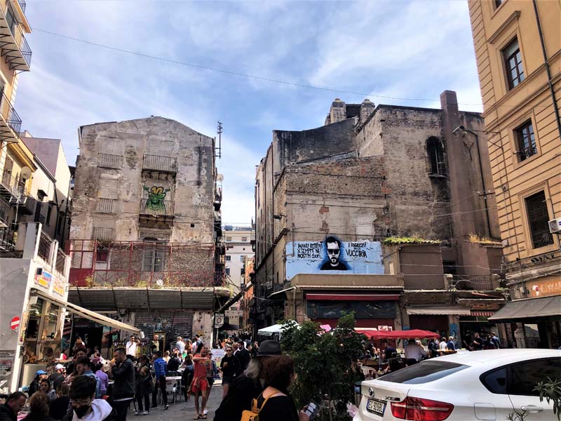 crowded marketplace with dilapidated buildings in background