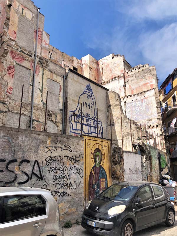 cars parked along dilapidated building with graffiti