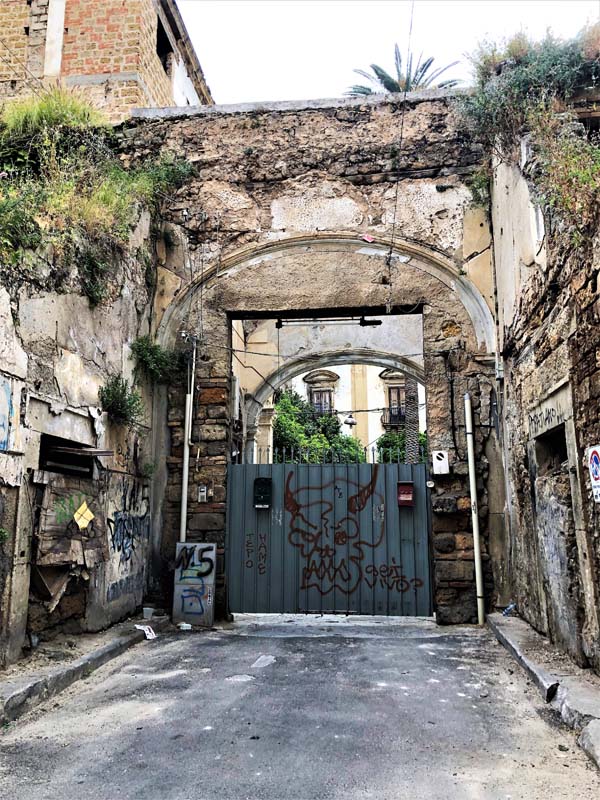 driveway entrance surrounded by graffiti-covered crumbling buildings