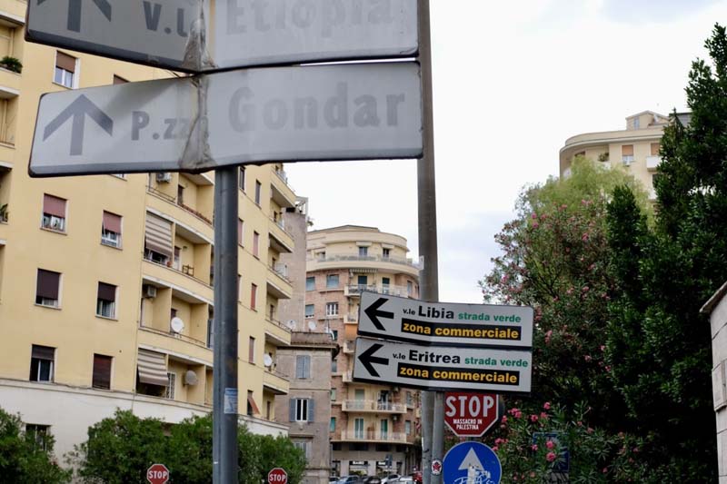 Street signs with mid-rise apartment buildings and trees in the background