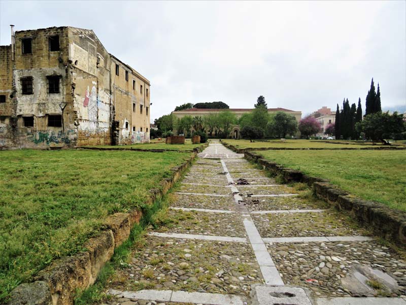 stone walkway through lawn, crumbling building to left