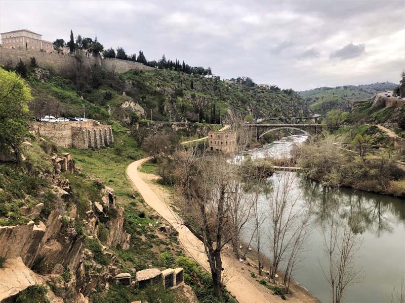 view of stone fortification, grassy hills, river with bridge