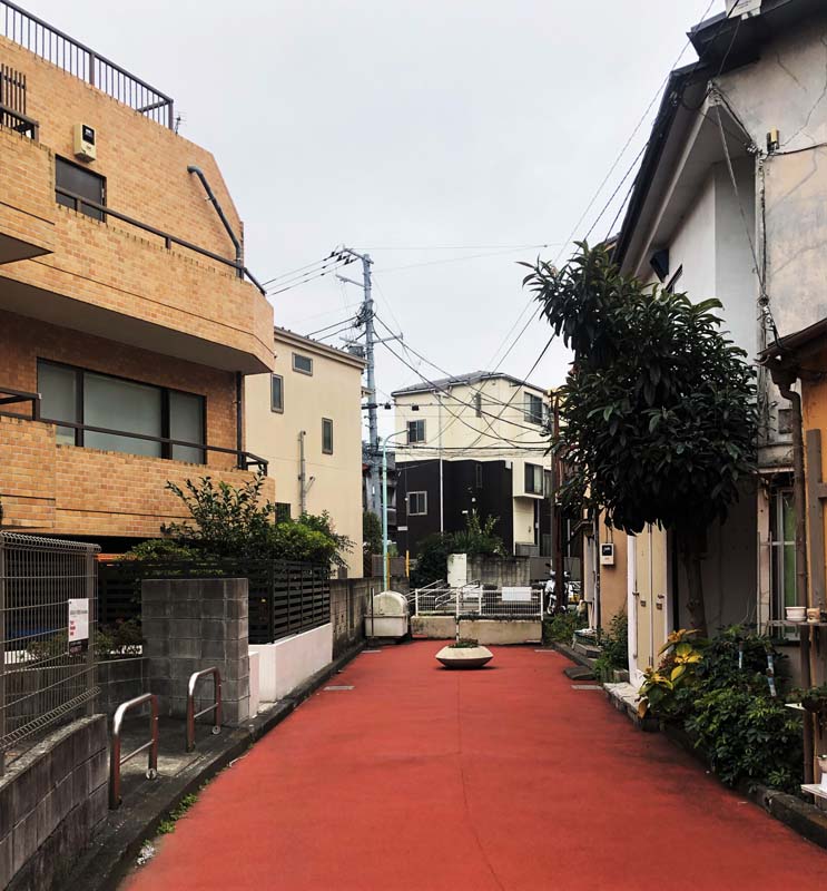 red pedestrian walkway flanked by lowrise buildings