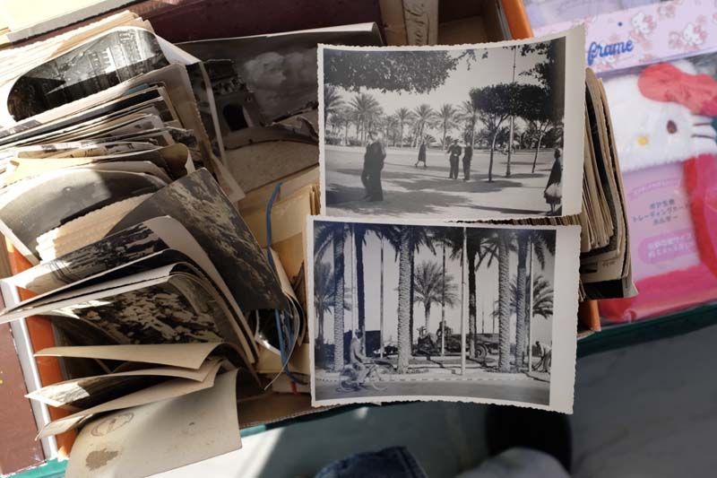 A box of black and white photographs next to a Hello Kitty photo frame