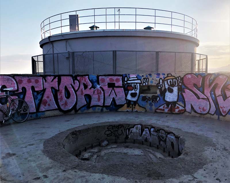 round concrete bunker with low wall covered with graffiti