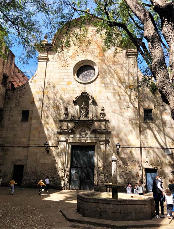 children play outside church, fountain in foreground