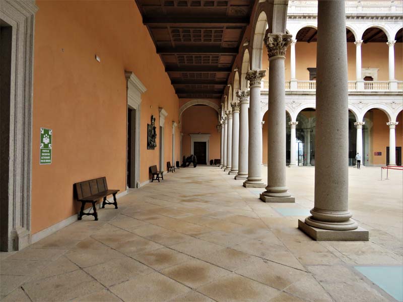 arcade with stone columns, stone floor, benches along wall