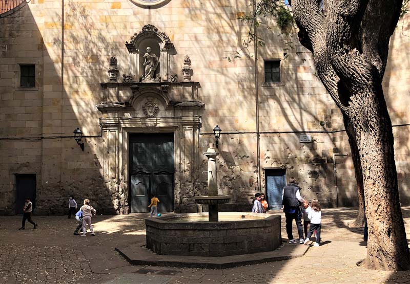 stone fountain and tree outside church, children playing