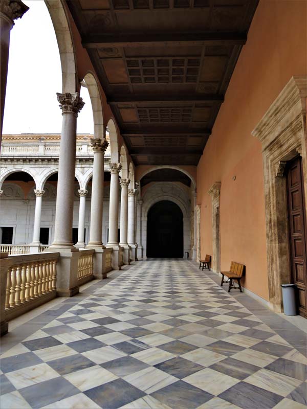 second-floor arcade with black and white tile floor, stone banisters