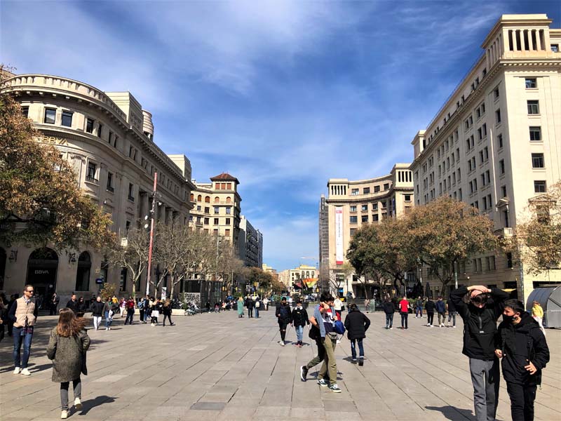 people walk in plaza among buildings