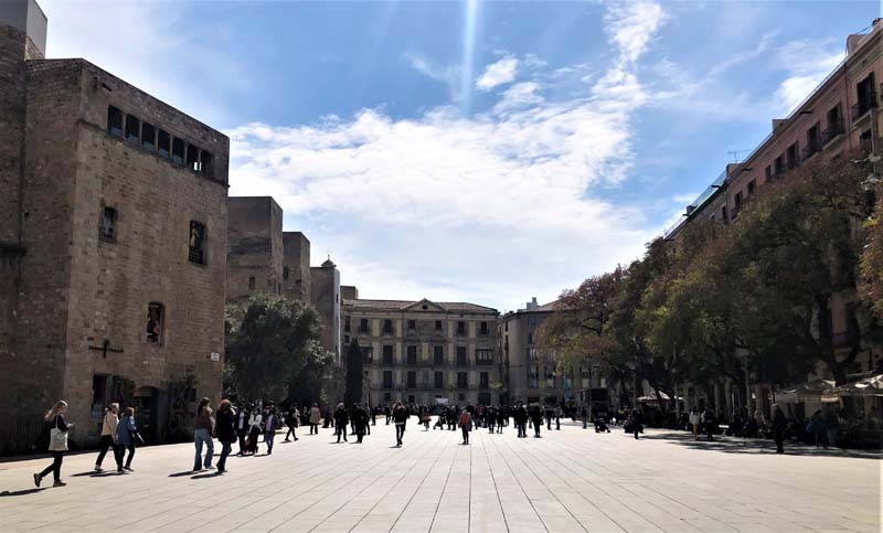 people walk on plaza among buildings