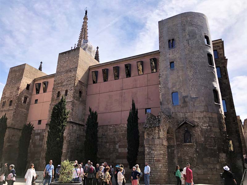 Roman walls and tower mixed with new construction, people in foreground