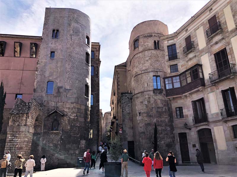 Roman towers with new construction, people walking in foreground