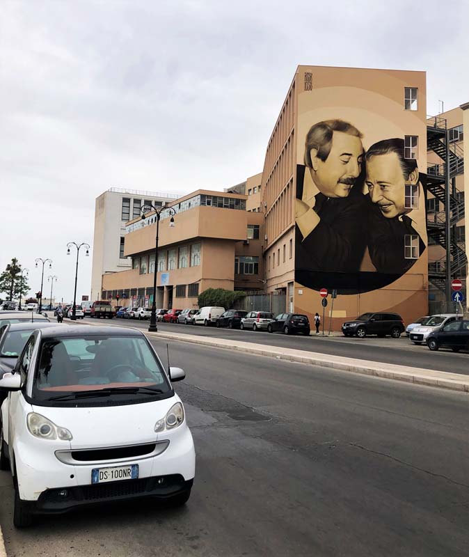 view from street of mural of two men on side of building