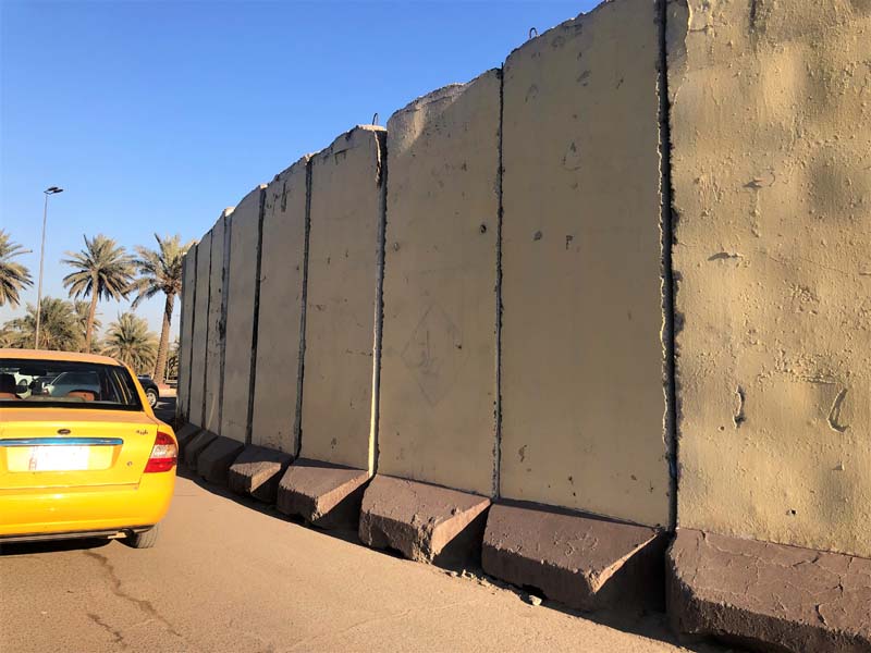 yellow car near a concrete wall, palm trees in background