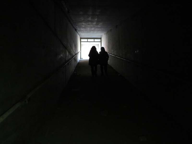 silhouette of two women walking down dark corridor to the light