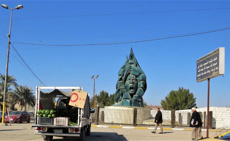 green sculpture of woman's head screaming with stylized flames