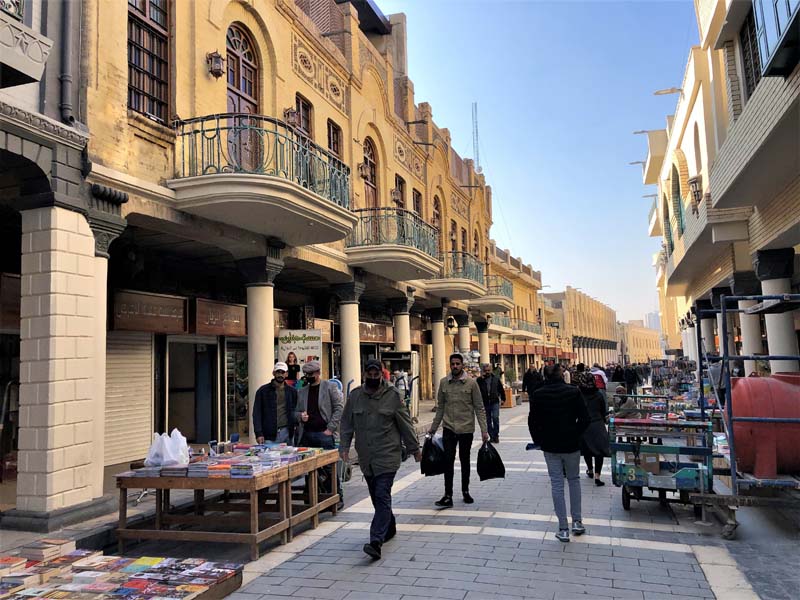 tables of books along walkway with two-story retail shops