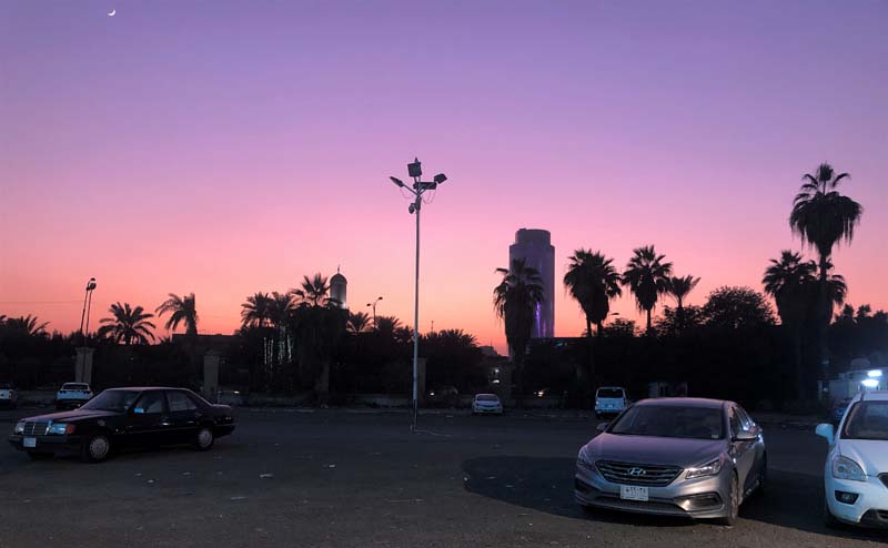 view of mall from parking lot at dusk with palm tree silhouettes