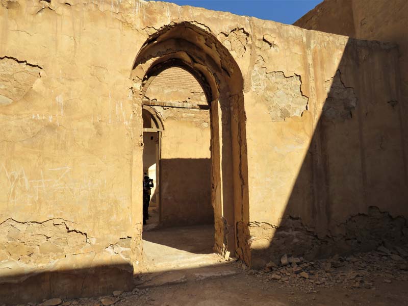 view through crumbling stone arched doorway into another room