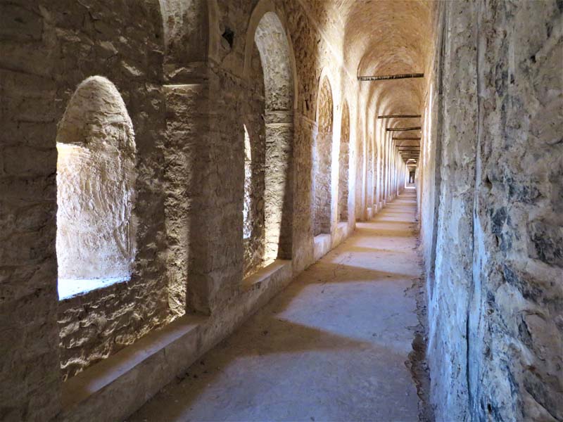 view down long corridor with stone barrel vault ceiling and arches