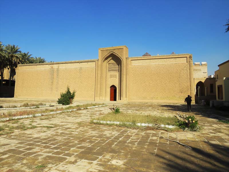 single-story building with patterned brickwork, pointed arch iwan