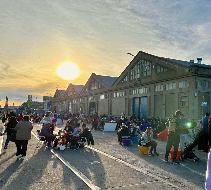 crowd of people outside industrial buildings at sunset