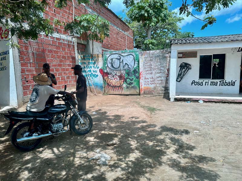 three men talk, graffiti on buildings in background