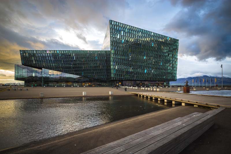 A large building uses angled hexagonal glass panes to add visual texture to some aspects while others have contrasting smooth surfaces