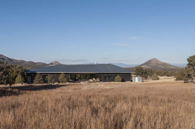 long rectangular house foregrounded by grassland, hills in background