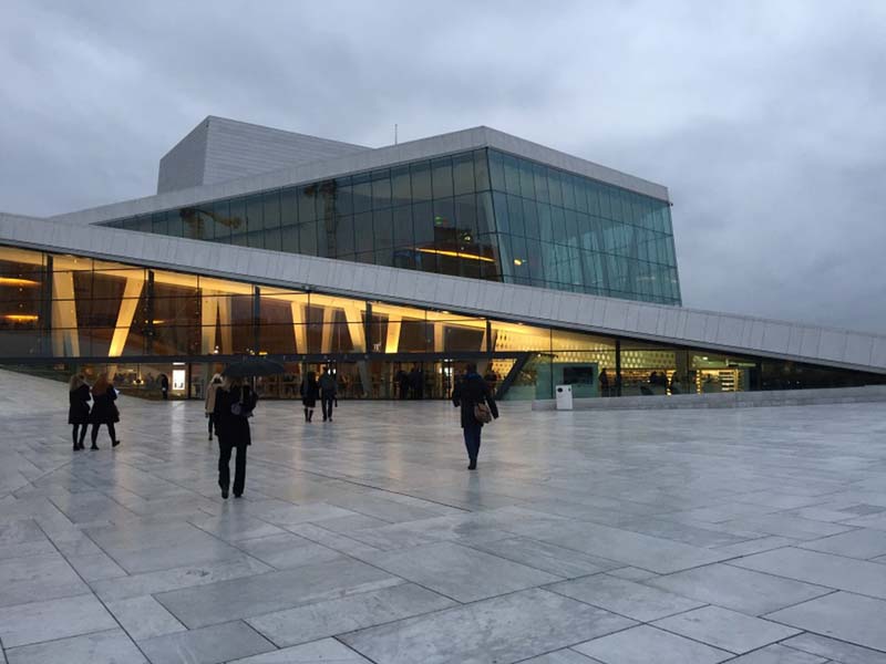 An open square leads to a building with angled rooflines and glass facades