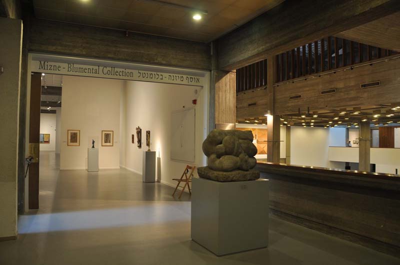 the interior of the Tel Aviv Museum of Art displays works on the walls and well as sculptures on white rectangular pedestals 