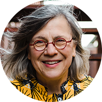 Woman with grey hair, glasses, and yellow shirt