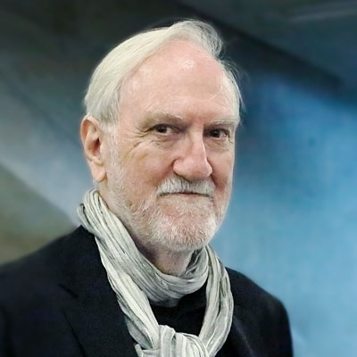 Anthony Vidler, a white man with white hair wears a black jacket and scarf.