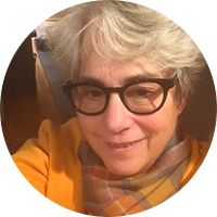 Woman with short grey hair, glasses, and yellow shirt