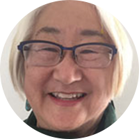 Lynne Horiuchi, an Asian woman with short white hair, wears glasses