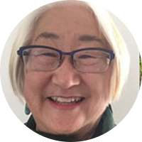 Asian woman with black glasses and white hair