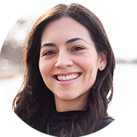 Krystal Racaniello, a woman with long, dark hair and a black blouse, smiles at the camera. 