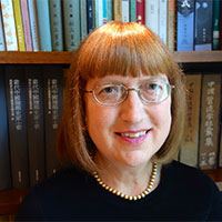 Nancy Steinhardt Stands in front of a full bookshelf