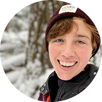 Talia Perry, a white woman, wears a beanie, coat and stand against a snowy background