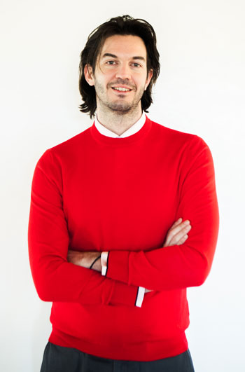 Stathis Yeros has dark hair and wears a red sweater