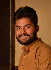 Sushant Bharti, an Indian man with beard, mustache and brown shirt smiles at the camera