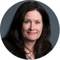 Lisa Tucker is a white woman with blue eyes and long, dark hair, smiling directly into the camera in front of a blue background.