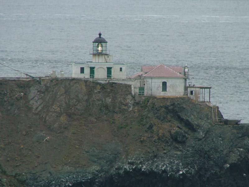 lighthouse buildings on cliff with view of ocean in background