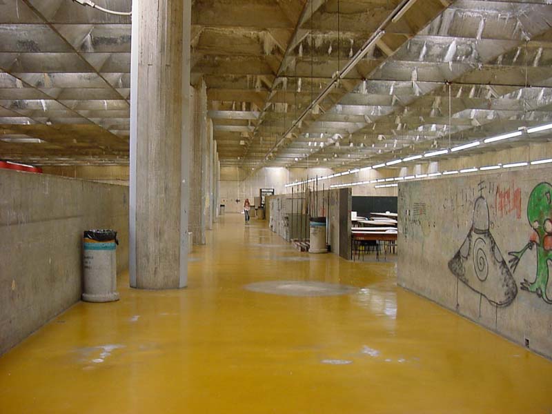large room with concrete pillars and yellow concrete floor