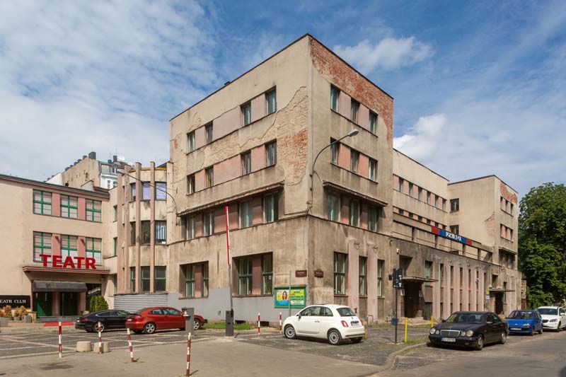 concrete building with cars parked in front