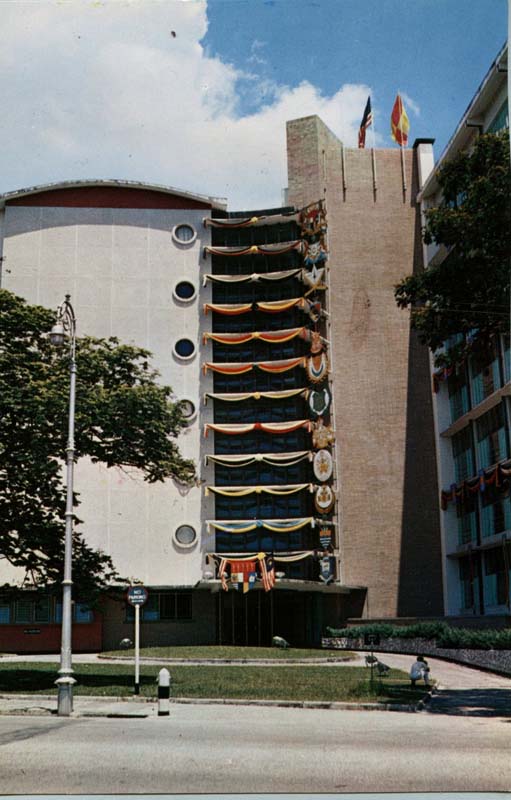 tall building with round windows and flags adorning the facade
